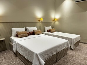 A hotel room with two beds, each with white bedding and multiple pillows. There are two wall-mounted lamps providing light. - Astro Vefa (Istanbul)