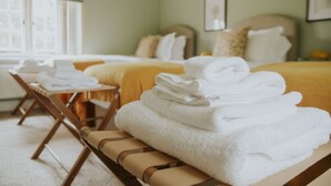 A hotel room with a bed, a bench with towels, and a window with blinds. - Kestrel Cottage in Castle Ashby (Northampton)