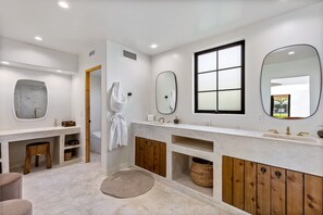Un baño moderno con un espejo grande, una bañera y un inodoro.