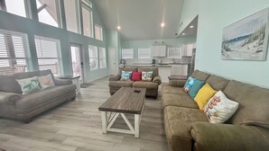 Amplia sala de estar con un amplio sofá, una mesa de centro y vista a la cocina a través de un espacio abierto.