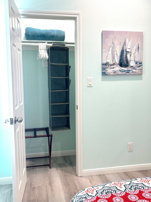 A walk-in closet with shelves, a hanging rack, and a door leading to another room.