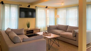 A modern living room with two sofas, a coffee table, a flat-screen TV, and a potted plant. - Casa Calypso-10 minutes to Newport and Narragansett. Walk to beach! (North Kingstown)