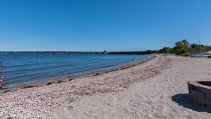 A beach with pebbles, a wooden structure on the water, and a clear sky. - Casa Calypso-10 minutes to Newport and Narragansett. Walk to beach! (North Kingstown)