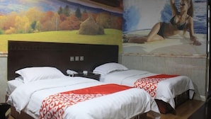 A hotel room with two beds, a large mural on the wall, and a view of the sea. - Yingbin Hotel (Rui'an)