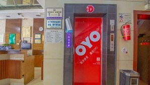 A reception area with a red OYO sign, a reception desk, and a fire extinguisher. - Yingbin Hotel (Rui'an)