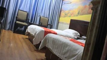 A room with two beds, a chair, and a mural on the wall.