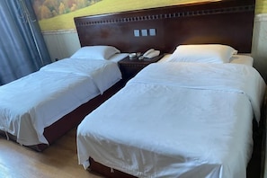 A hotel room with two single beds, a wooden headboard, a nightstand with a phone and a lamp, and a mural on the wall. - Yingbin Hotel (Rui'an)