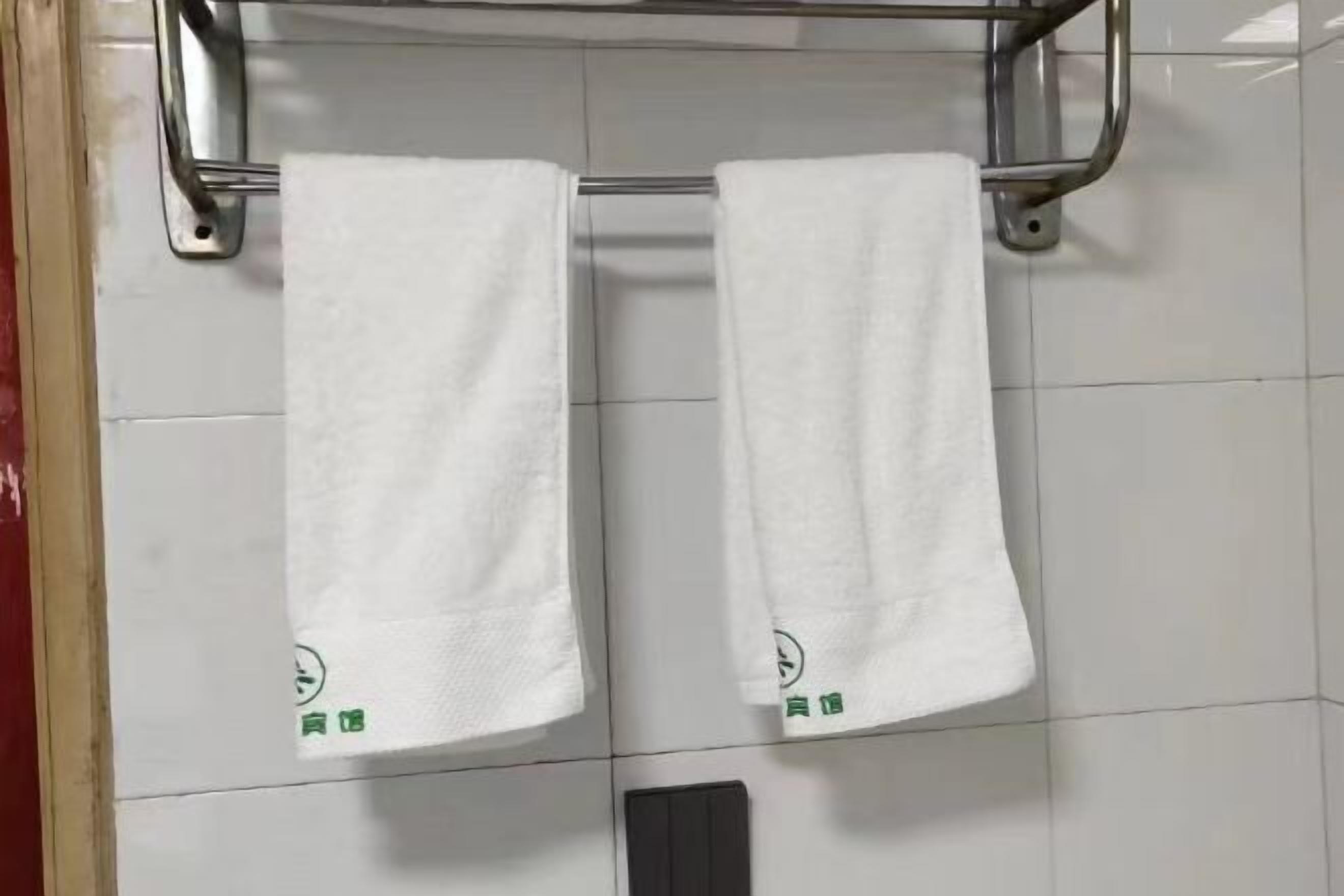 A bathroom with two white towels hanging on a metal rack.
