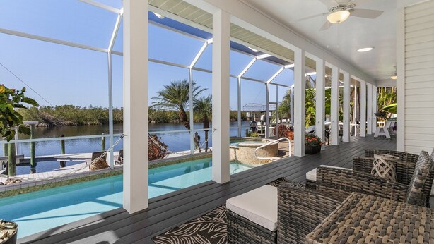 A covered outdoor area with a pool, seating, and a view of a body of water. - VILLA "EAGLE'S NEST"  THREE STORY HOME WITH AMAZING VIEWS (Cape Coral)
