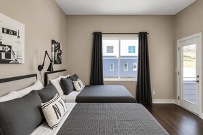 A bedroom with two beds, a window with curtains, a lamp, and a wall with a street sign. - Nashville Vacation Stay • Views & Hot Tub (Nashville)