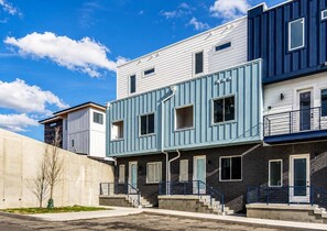 A row of townhouses with a concrete retaining wall, a small tree, and a clear blue sky. - Nashville Vacation Stay • Views & Hot Tub (Nashville)