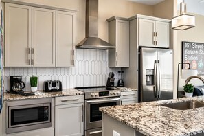 A modern kitchen with stainless steel appliances, a granite countertop, and a backsplash with a geometric pattern. - Nashville Vacation Stay • Views & Hot Tub (Nashville)