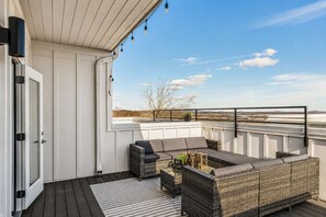 Terraza en la azotea con mobiliario de mimbre, vistas del paisaje y cielo despejado.
