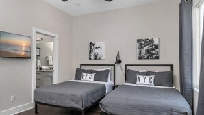 Un dormitorio con dos camas, ventilador de techo, obras de arte y vistas al exterior.