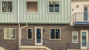 Un edificio residencial de varios pisos con fachada de ladrillo, múltiples ventanas y una escalera visible que conduce a la entrada.