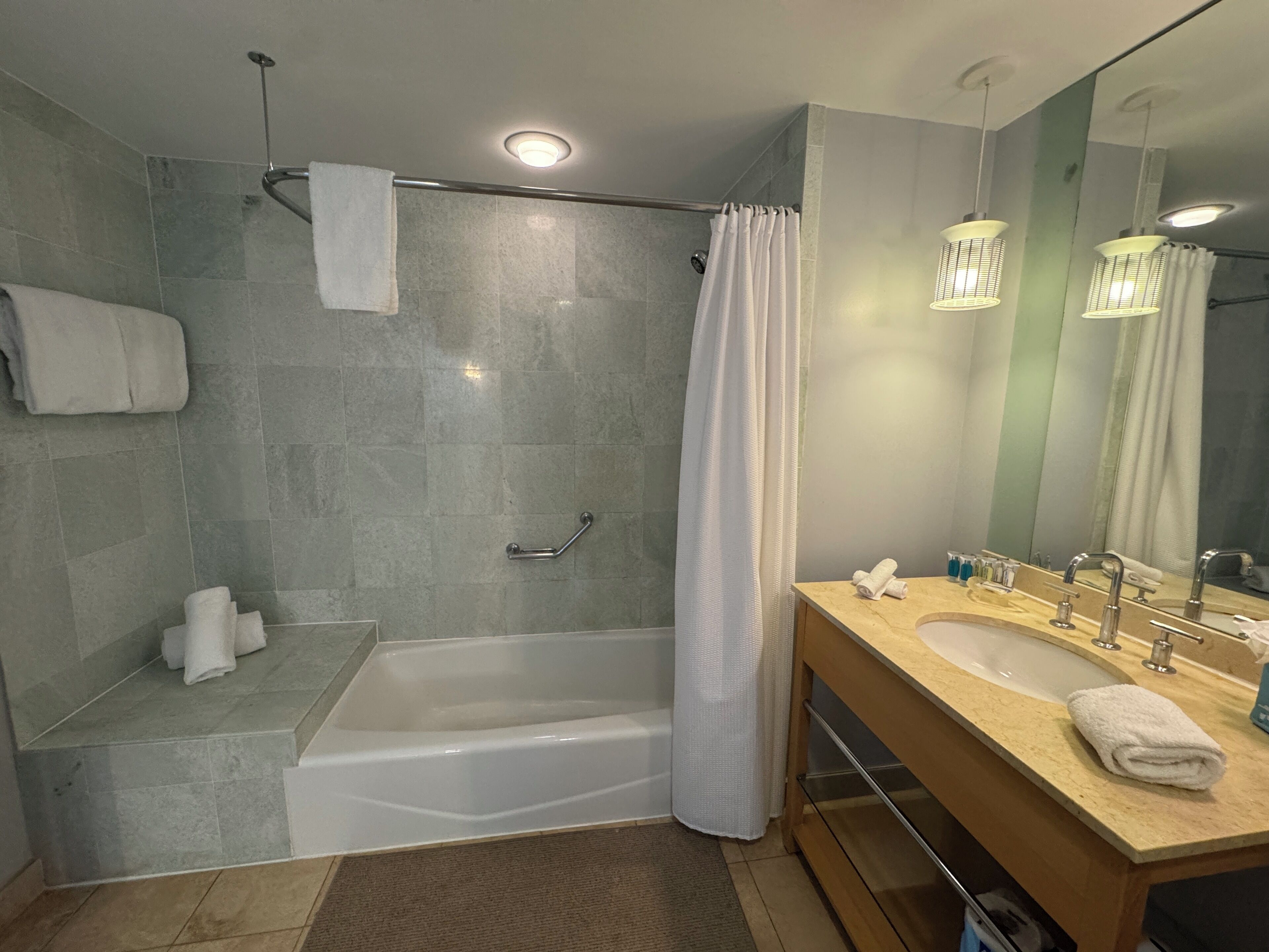 A modern bathroom with a bathtub, shower, and vanity.