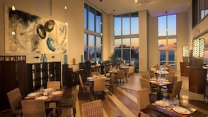 A spacious dining area with high ceilings and large windows offering views of the ocean. - Marenas Beach Resort (Sunny Isles Beach)