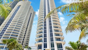 Two high-rise buildings with multiple balconies, surrounded by palm trees. - Marenas Beach Resort (Sunny Isles Beach)