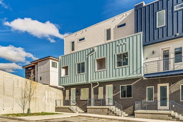 A modern multi-story residential building with a flat roof, large windows, and a concrete retaining wall. - New Nashville Escape • Hot Tub & Skyline Views (Nashville)