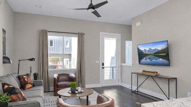 Una sala de estar moderna con sofá, sillón, mesa de centro y televisor montado en la pared.