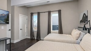 Un dormitorio con dos camas, un escritorio, una ventana con cortinas y un cuadro en la pared.