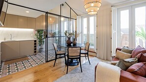 A modern kitchen with a glass partition, a dining area with a round table and chairs, and a cozy seating area with a sofa and cushions. - Bonfim Elegant Duplex w/ AC by LovelyStay (Porto)