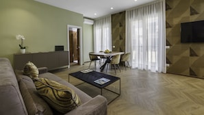 A modern living room with a sofa, a coffee table, and a dining area with chairs and a table. - Dreamers' Rooms Sorrento (Sorrento)