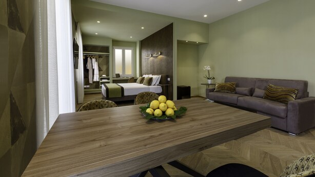 A modern living room with a wooden dining table, a sofa, and a bed in the background. - Dreamers' Rooms Sorrento (Sorrento)