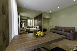 A modern living room with a wooden dining table, a sofa, and a bed in the background. - Dreamers' Rooms Sorrento (Sorrento)