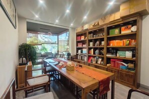 A dining area with a wooden table, chairs, and shelves stocked with various items. - Mimengyitan Holiday Inn (Deqing)
