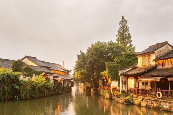 A traditional canal-side building with a wooden walkway and a bridge. - Mimengyitan Holiday Inn (Deqing)