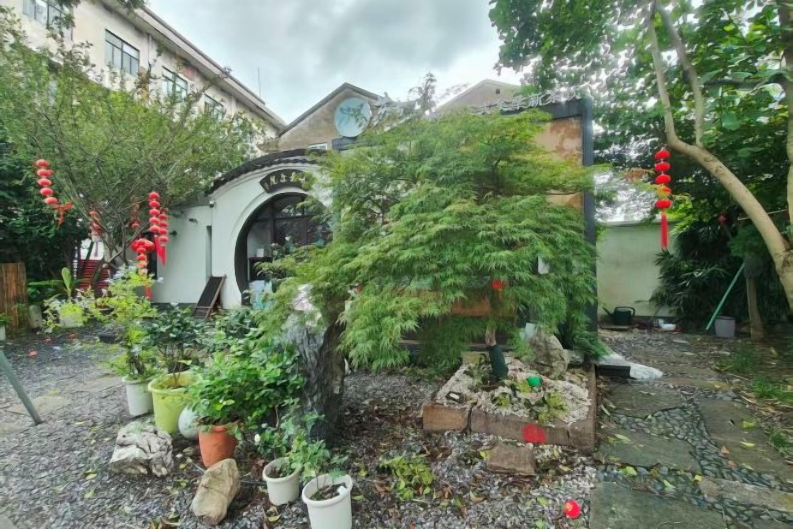 A garden with a variety of plants and a small building with an arched entrance.