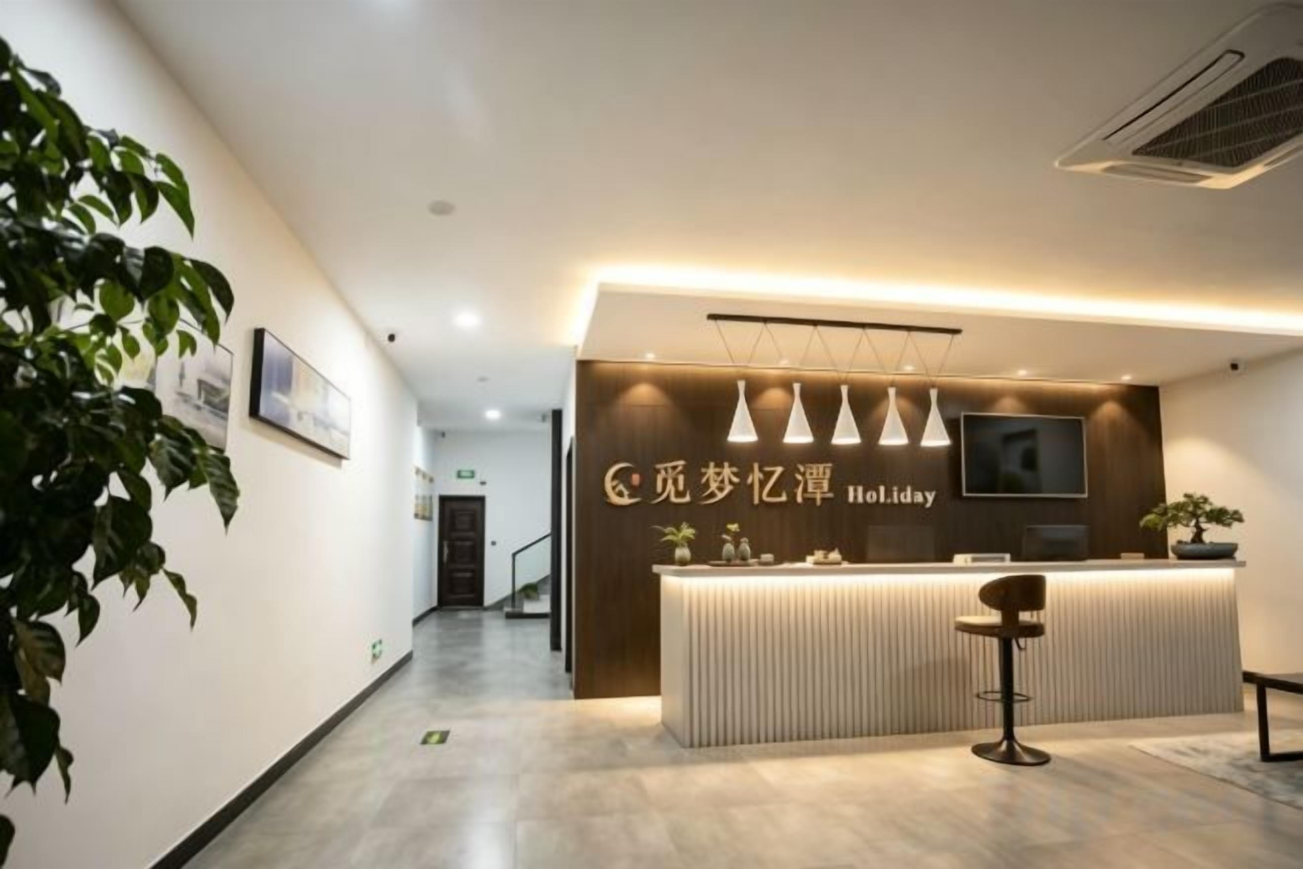 A reception area with a modern design, featuring a reception desk, a television, and a potted plant.