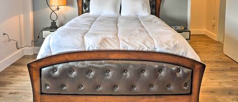 A neatly made bed with a wooden headboard and a bedside lamp.