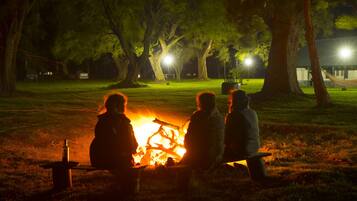 A group of people sitting around a campfire in a park at night.