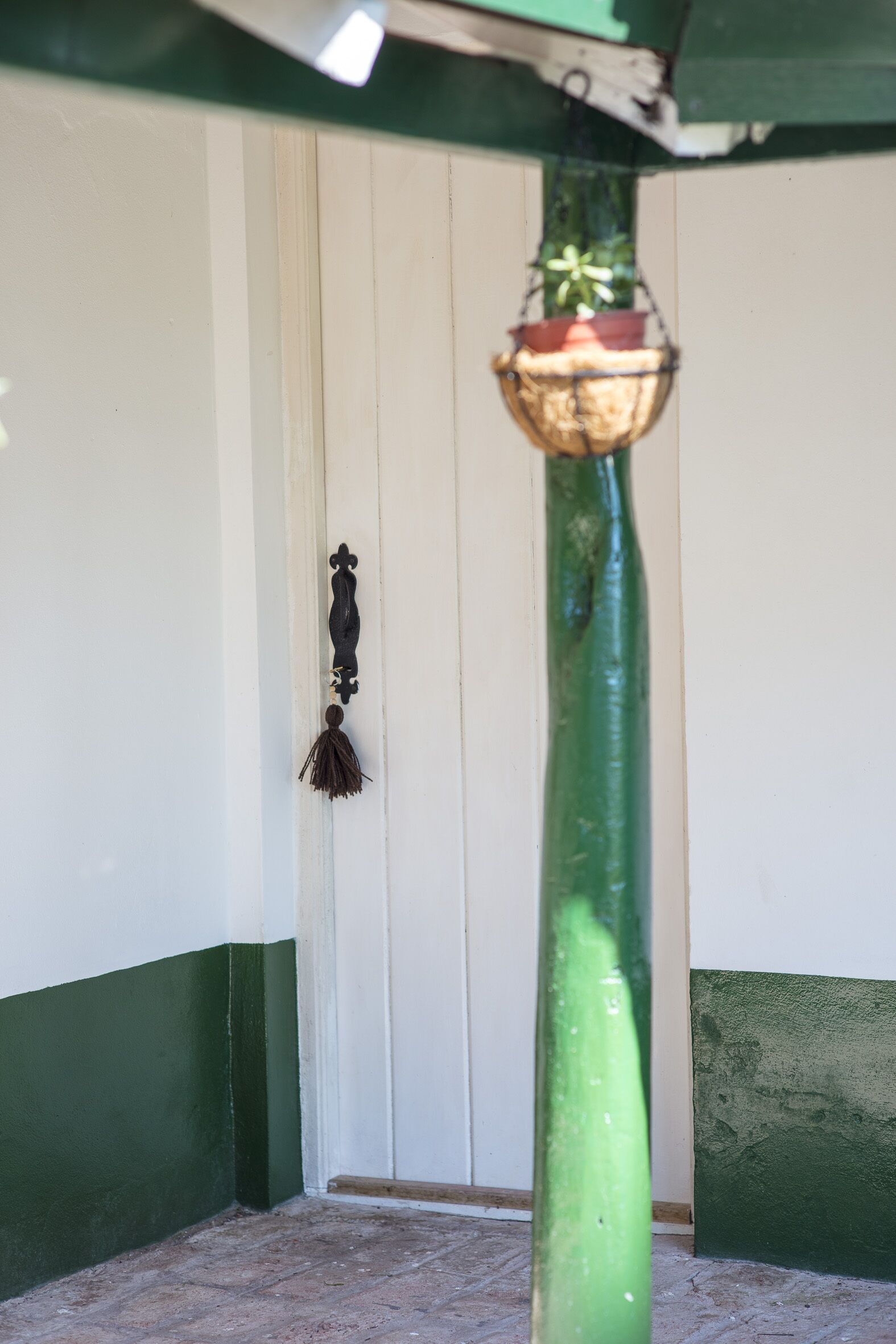A green pole with a hanging planter and a black wall-mounted decoration.
