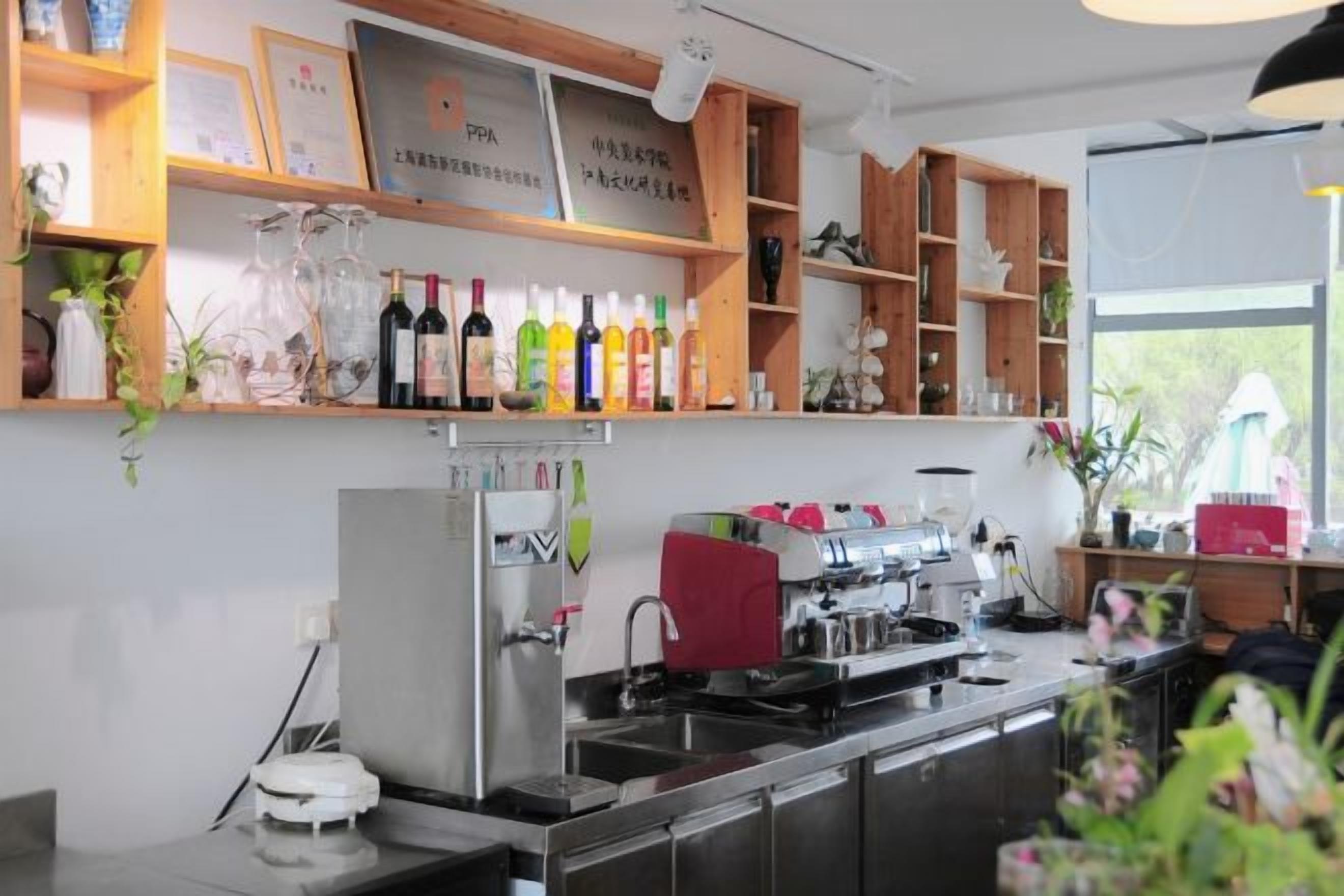 A kitchen with a coffee machine, shelves with bottles, and a window.