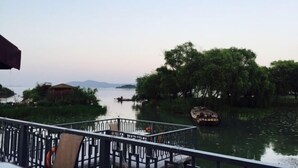 Vista sul fiume con un molo di legno, una barca e vegetazione rigogliosa.