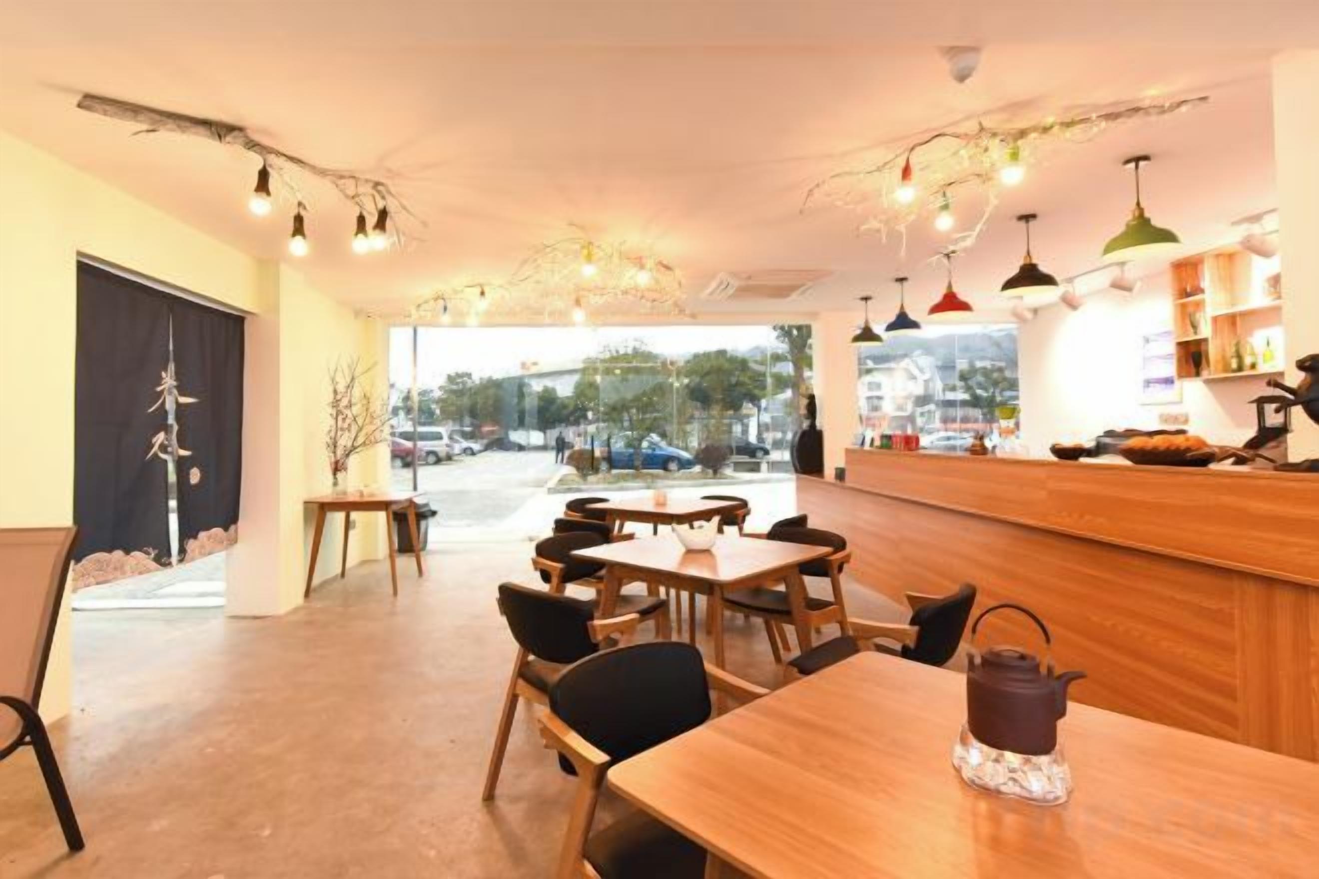 Interior de restaurante con mesas, sillas, una barra y lámparas colgantes.