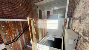 A kitchen with a refrigerator, a wooden staircase, and a brick wall. - RVA Arts District near VCU MCV (Richmond)