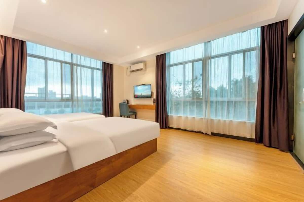 Une chambre d’hôtel avec un grand lit, un bureau, une télévision et de grandes fenêtres.