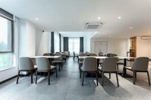 Uma sala de conferências com várias mesas e cadeiras, janelas amplas e design moderno.