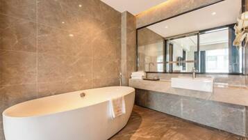 A modern bathroom with a freestanding bathtub, a large mirror, and a marble countertop.