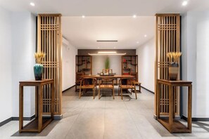 A modern dining area with a wooden table and chairs, flanked by two tall, open wooden partitions. - Jiangmen Jinli Hotel (Siqian Town Center Avenue Branch) (Jiangmen)