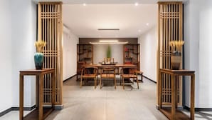 A modern dining area with a wooden table and chairs, surrounded by wooden partitions and shelves with decorative items. - Jiangmen Jinli Hotel (Siqian Town Center Avenue Branch) (Jiangmen)