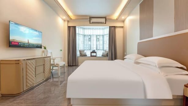 A hotel room with a bed, a TV on the wall, a desk, and a window with curtains. - Jiangmen Jinli Hotel (Siqian Town Center Avenue Branch) (Jiangmen)