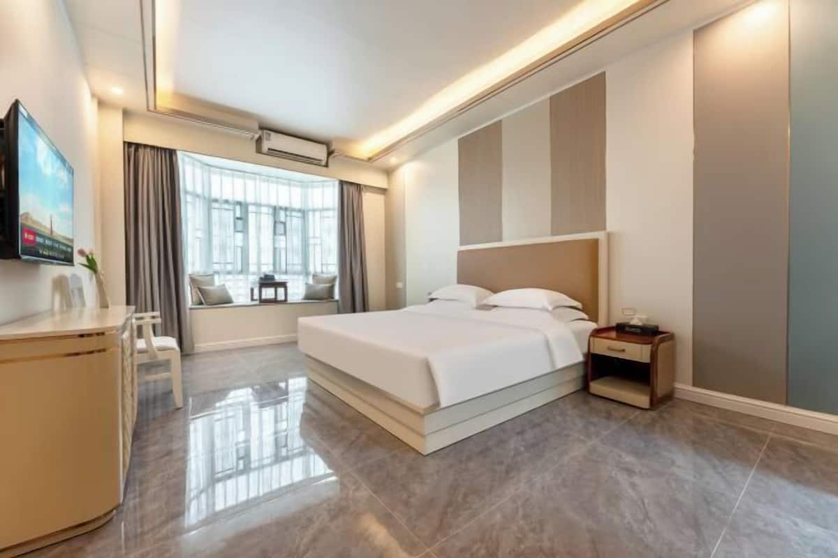 Une chambre d’hôtel moderne avec un grand lit, un bureau et un téléviseur fixé au mur.