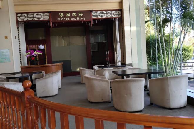 A seating area with tables and chairs, a wooden staircase, and a building entrance with a sign.