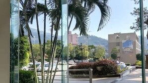 A view from a window with a table and chairs, overlooking a street with cars and buildings, palm trees, and a hilly landscape. - Hua'an Hotel (Hua'an)