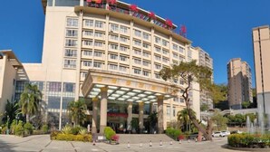 A multi-story hotel with a prominent entrance, a covered area with columns, and a clear sky. - Hua'an Hotel (Hua'an)